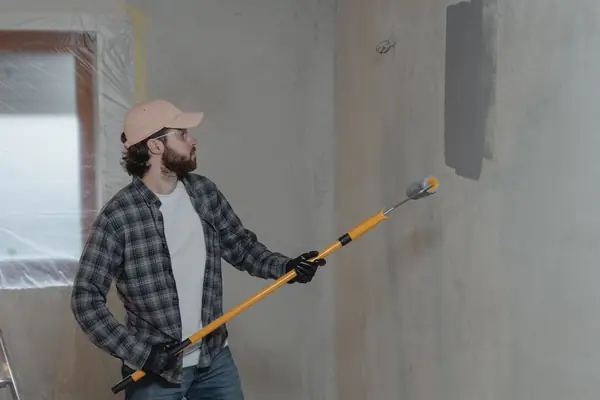 Painter rolling grey paint onto an interior wall in Jackson