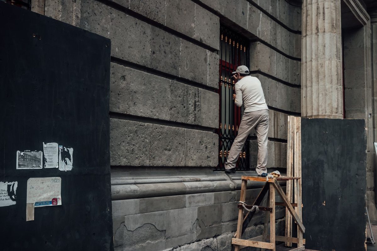 Worker on scaffolding at a dark stone facade